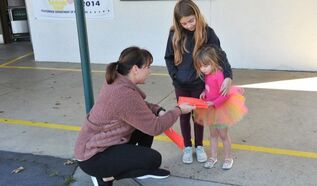 A woman handing something to two girls.  